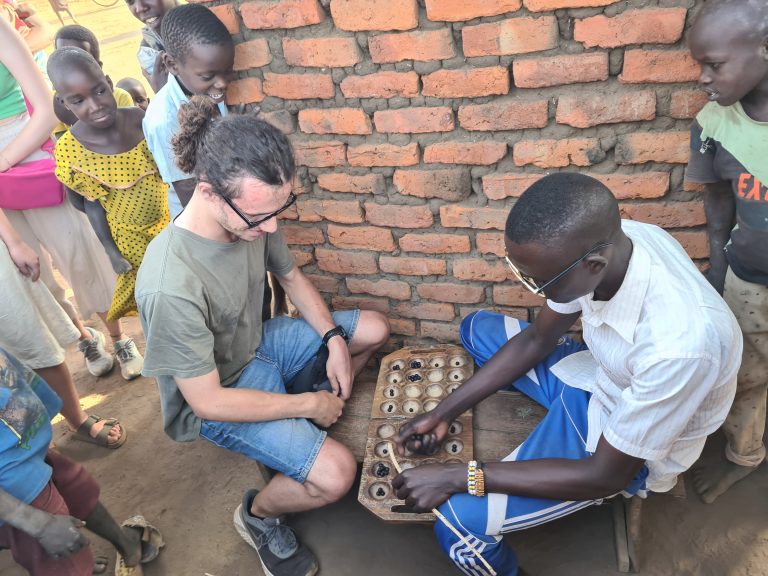 Tourist playing local board game umwezo in Karamoja, Uganda